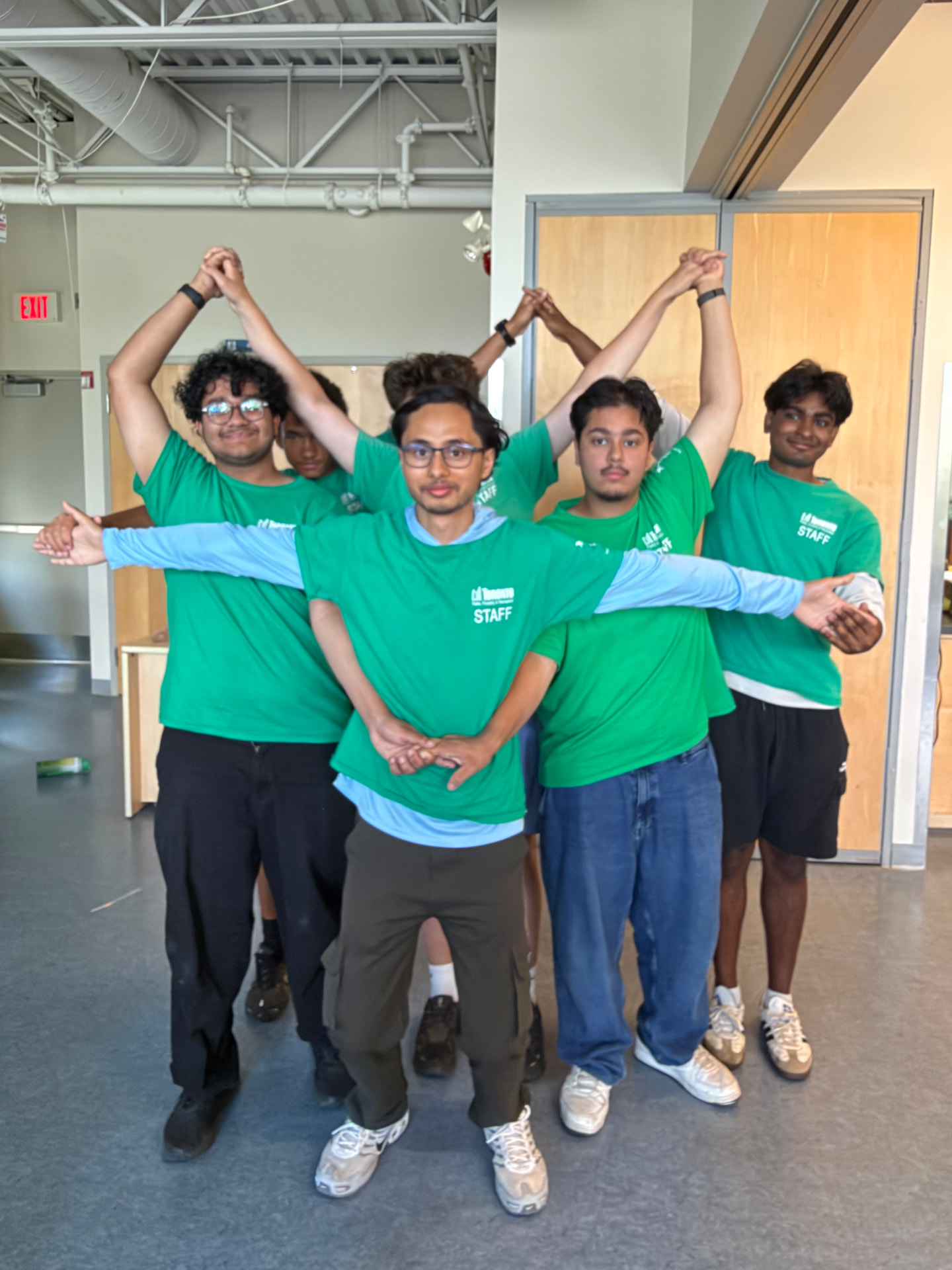 Camp staff forming a human arch with raised clasped hands over a T-posing counselor