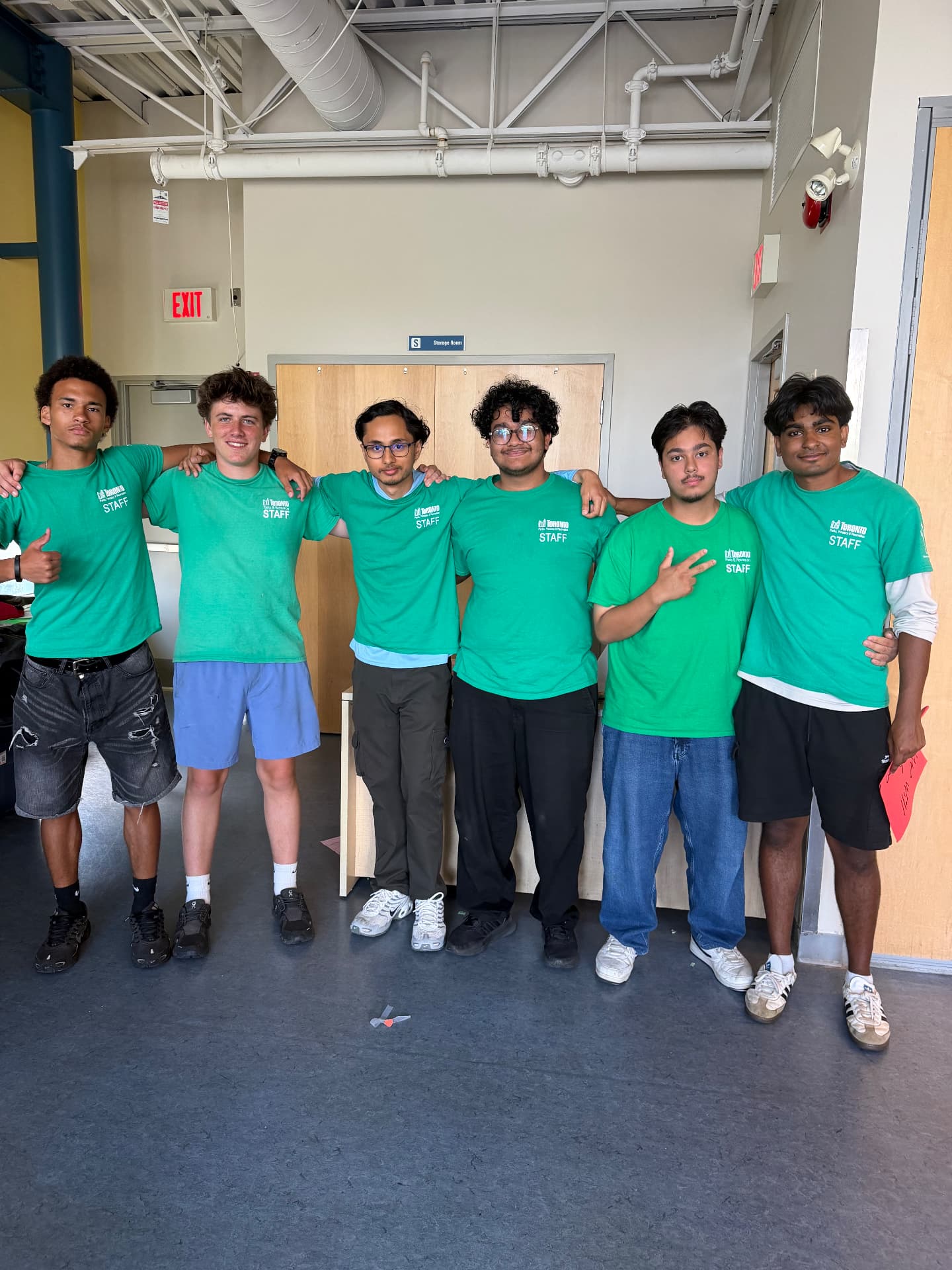 Six camp staff in green Toronto Parks & Recreation shirts standing shoulder to shoulder
